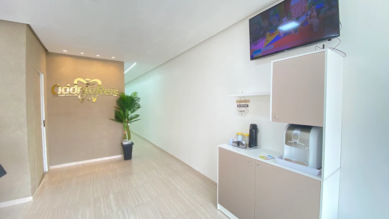 Corredor interno com logotipo dourado da OdontoReis e espaço de café